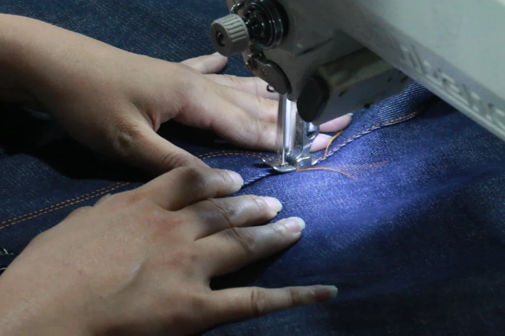 Couturière qui coud un jean épais à la machine à coudre